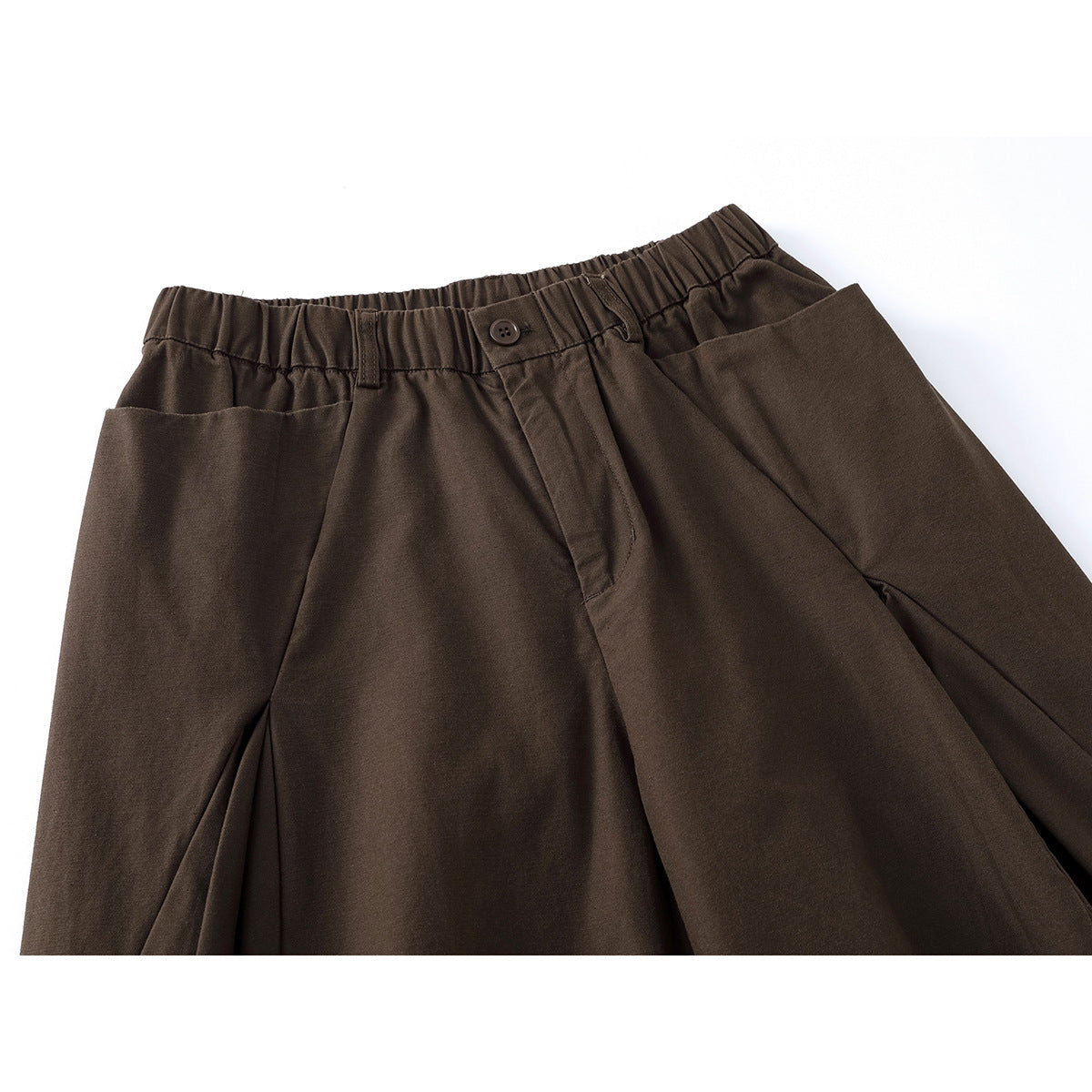 Close-up of dark brown wide-leg pants showing the elastic waistband, button closure, and front pleats.