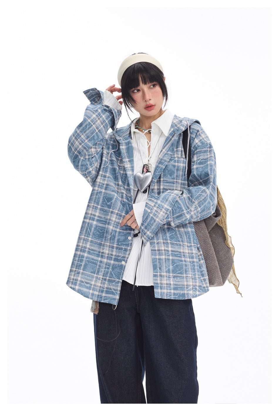 Closer front view of a model wearing an oversized blue-and-white plaid hooded shirt jacket over a white blouse.