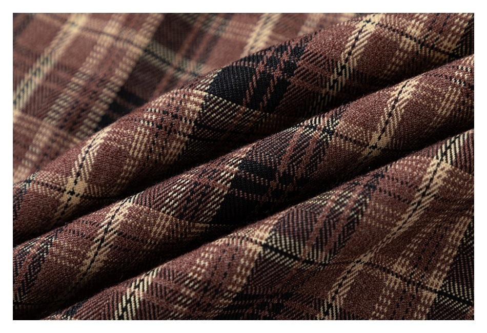 Close-up of brown, black, and cream plaid fabric arranged in soft folds.