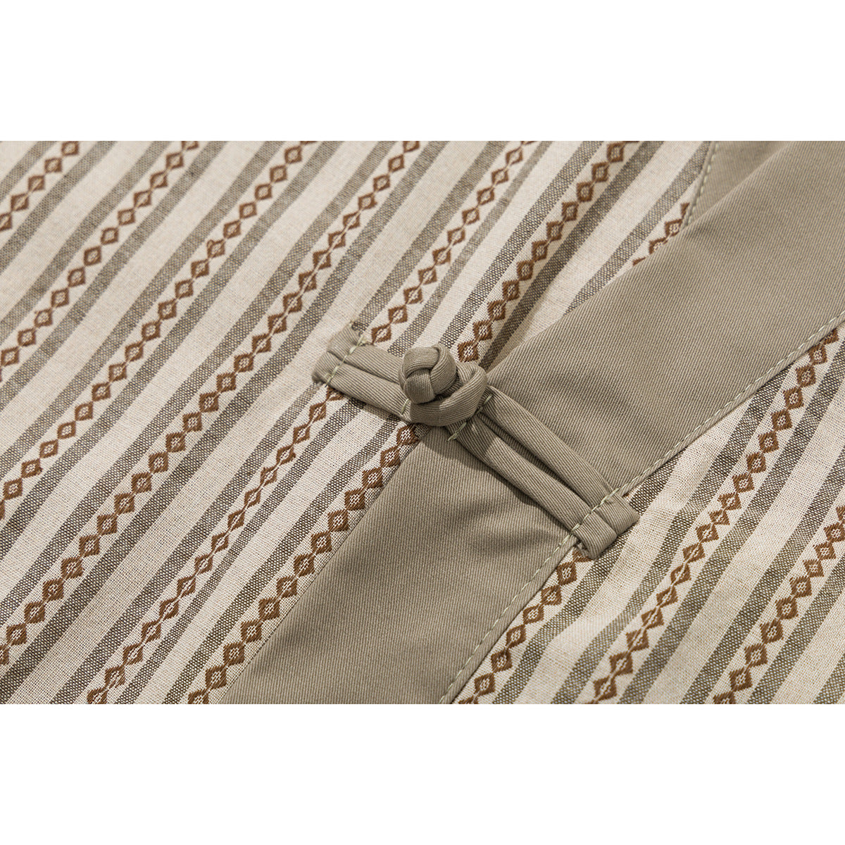 Close-up of a knotted frog closure on the beige and brown striped shirt.