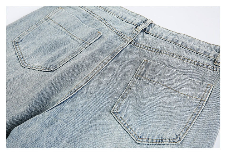 Close-up of light blue jeans showing two rear pockets, belt loops, and contrast stitching.