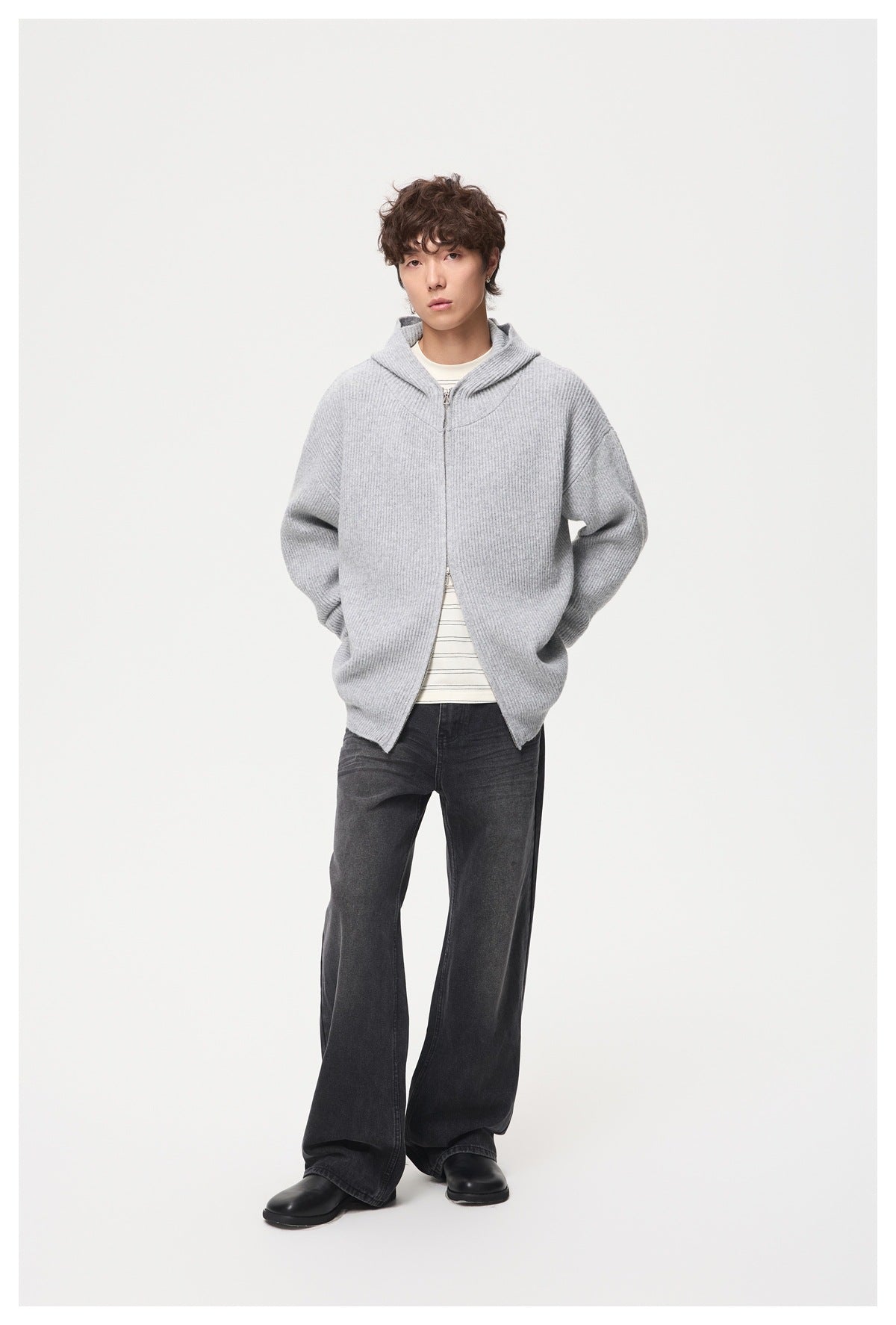 Model wearing dark charcoal wide-leg jeans with a light gray zip-front hooded cardigan and striped shirt.