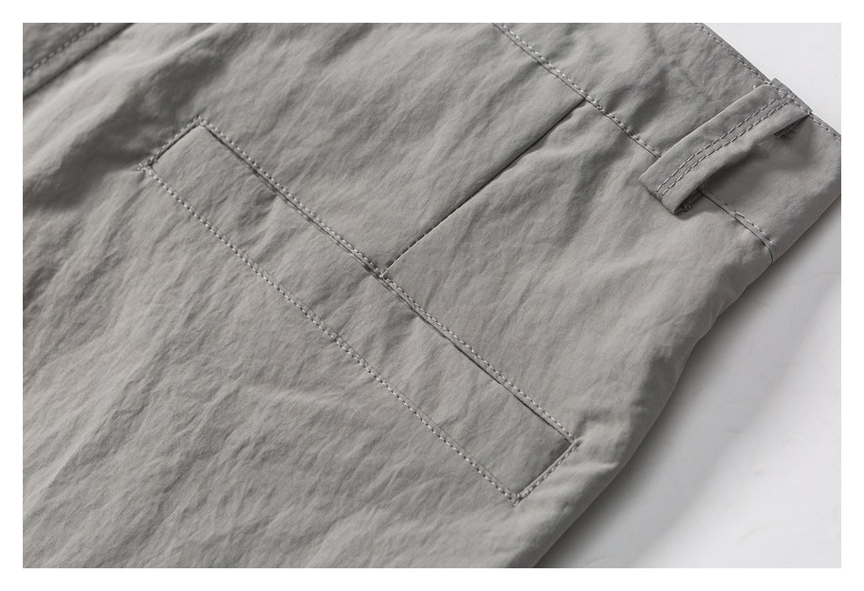 Close-up of a gray garment showing a stitched patch pocket and belt loop.