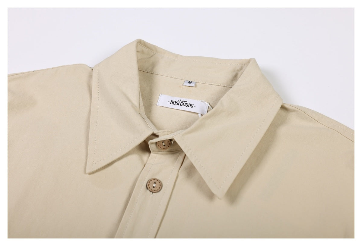 Close-up of the beige shirt's pointed collar, top buttons, and sewn neck labels.