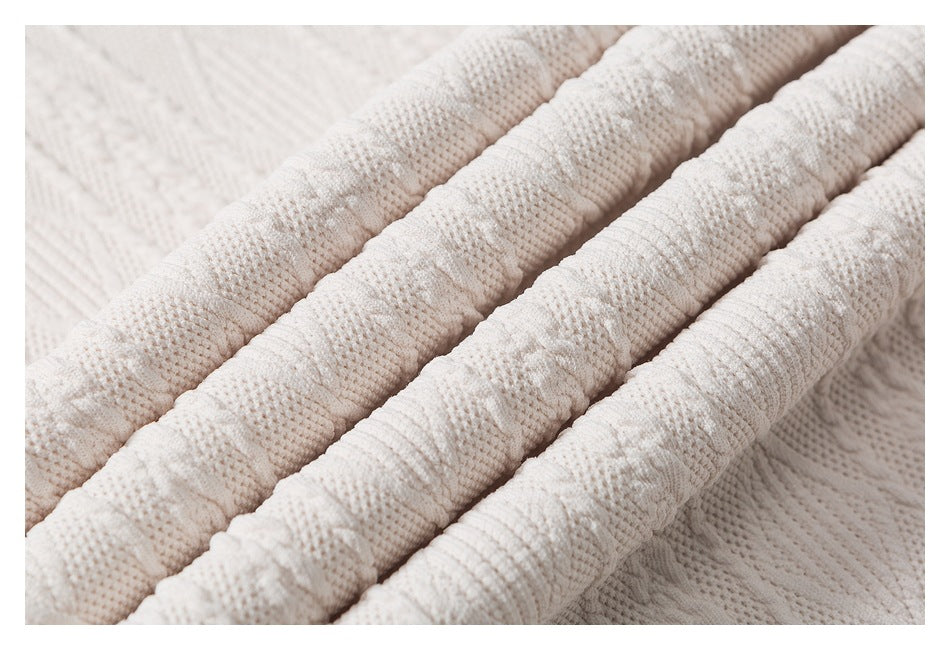Close-up of off-white textured knit fabric folded into several diagonal ridges.