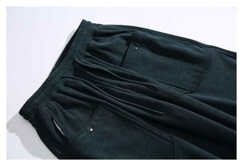 Close view of dark teal pants showing the elastic waistband, drawstrings, and snap-button front pockets.