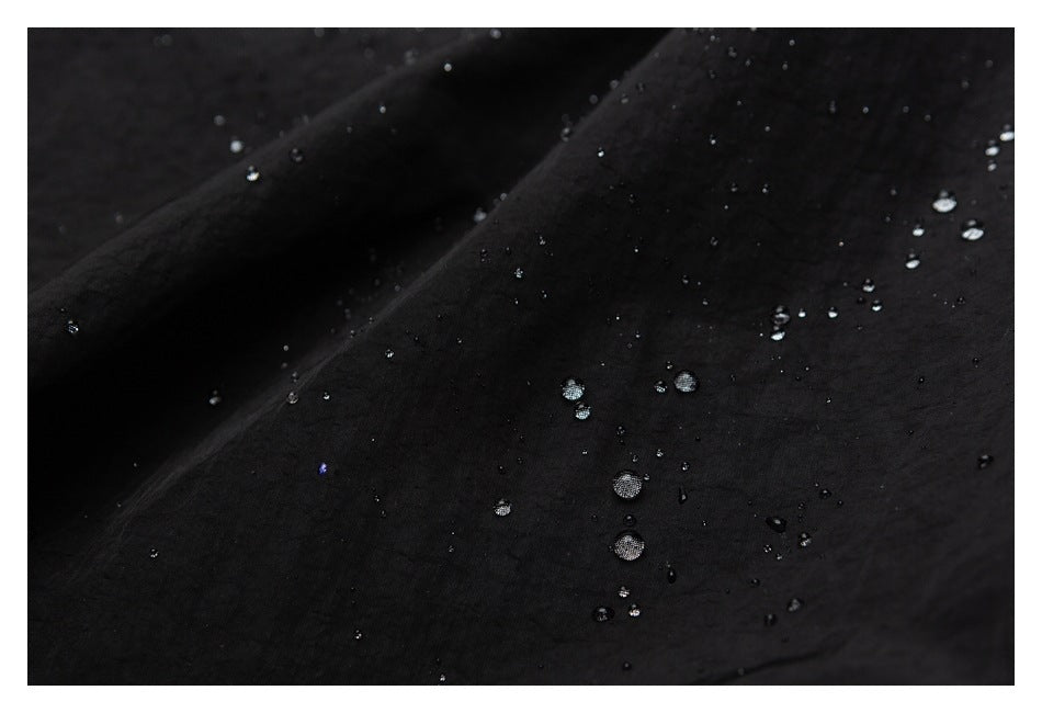 Close-up of black fabric with water droplets beading on its surface.