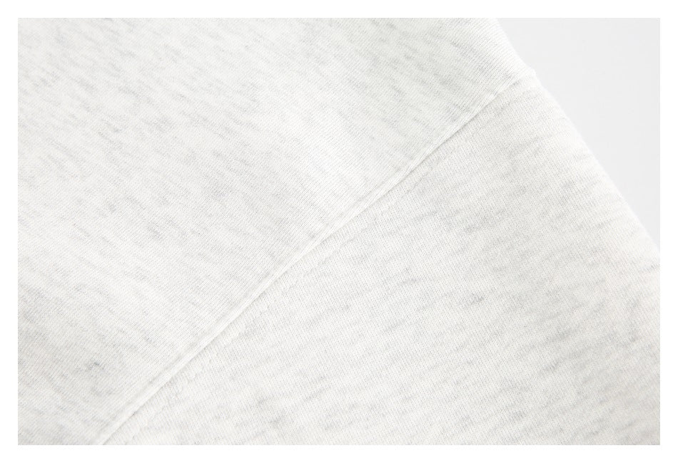 Close-up of a diagonal stitched seam on light heather-gray sweatshirt fabric.