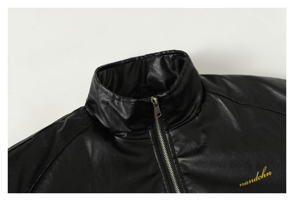 Close-up of a black jacket collar and silver zipper, with small gold script on the chest.