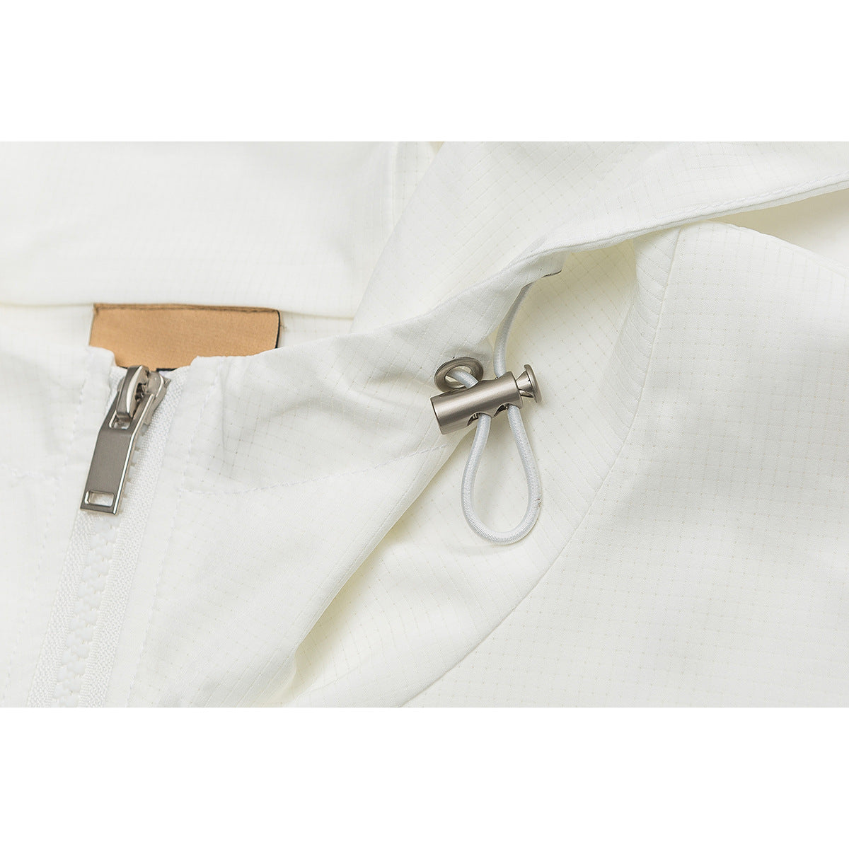 Close-up of a white hooded jacket showing the front zipper, metal zipper pull, and drawcord toggle.