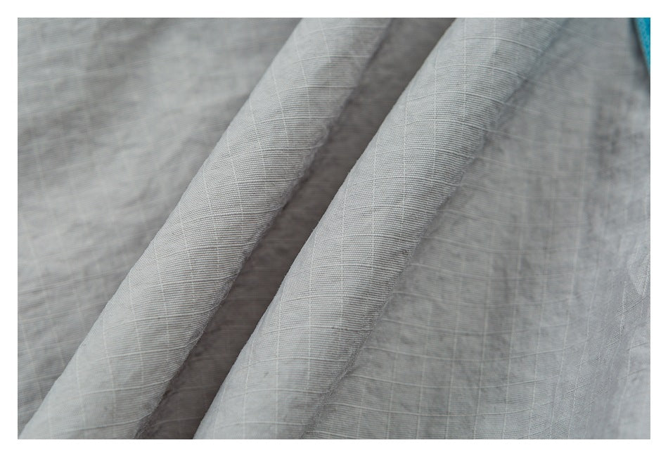 Close-up of light gray woven fabric with a subtle crosshatch texture and overlapping folds.