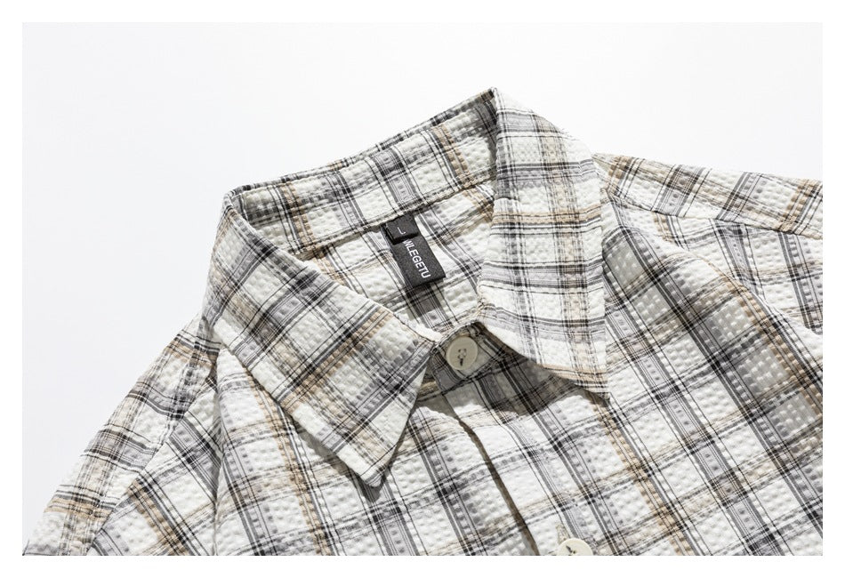 Close-up of the cream plaid shirt's pointed collar, neckline, and front button.
