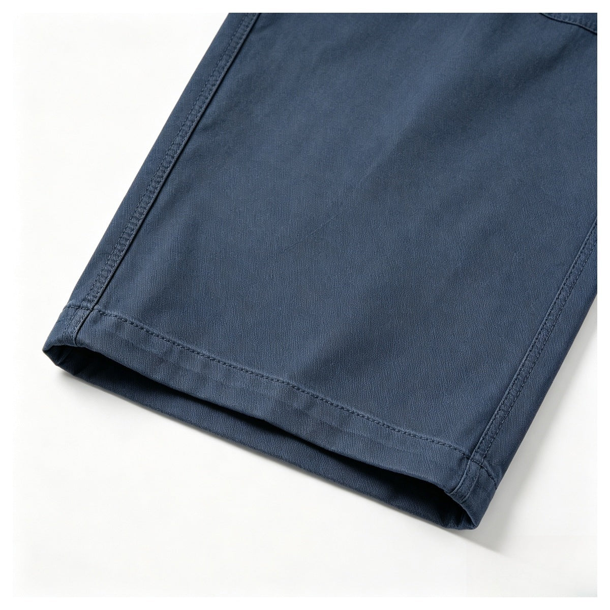 Close-up of the hem and stitching on dark navy trousers against a white background.