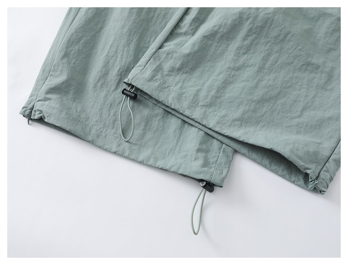 Close-up of sage green pant hems with adjustable drawcords and black cord locks.