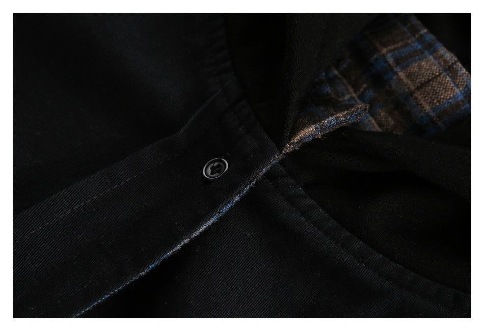 Close-up of a black jacket button and seam beside brown and blue plaid lining.