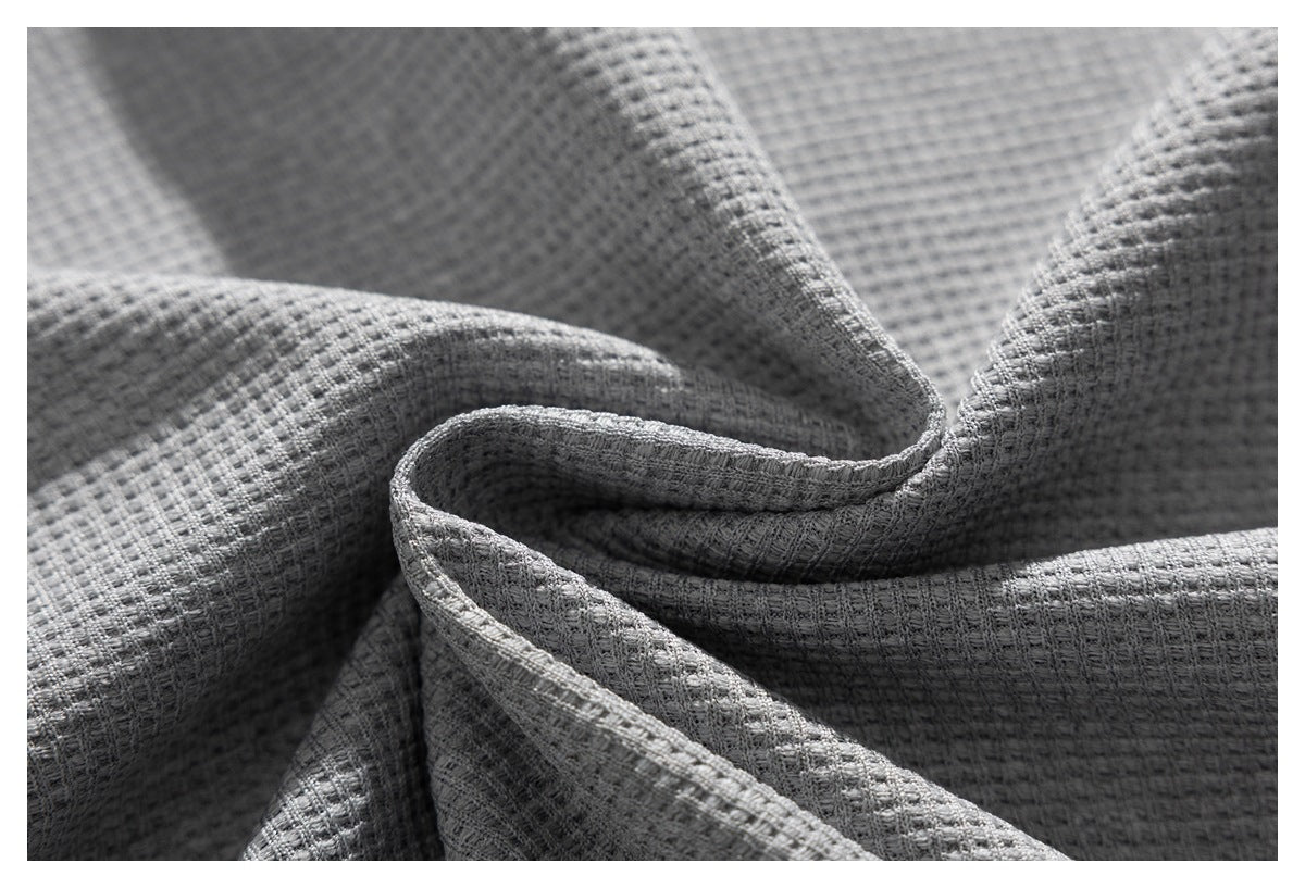 Close-up of gray fabric folded into soft ridges, showing a pronounced textured weave.
