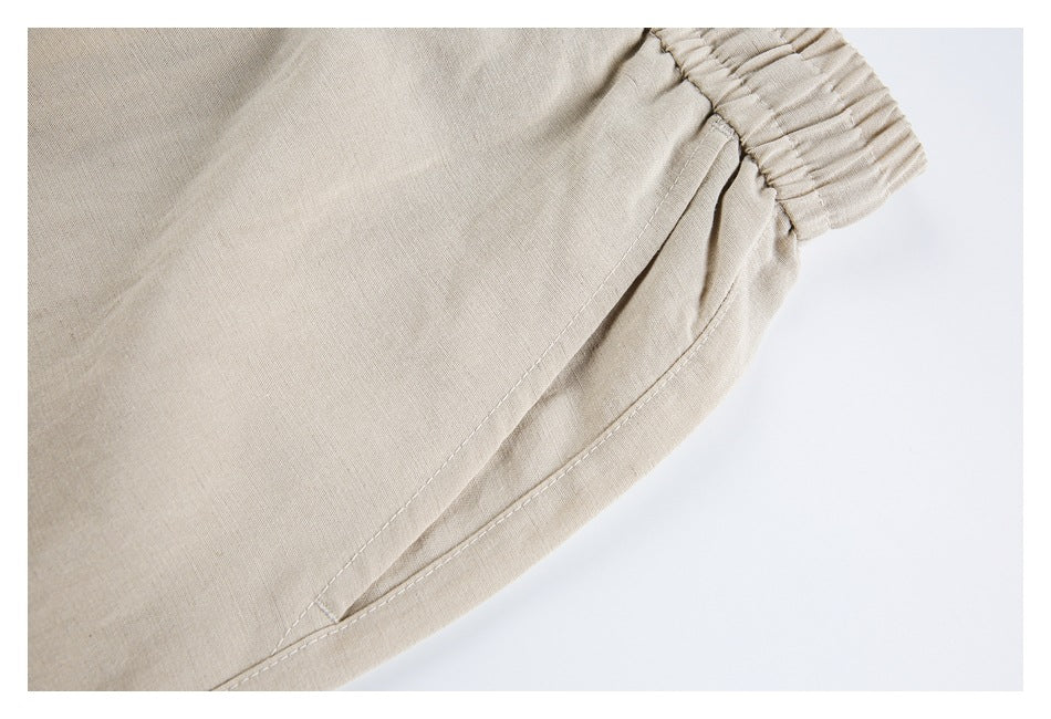 Close-up of beige trousers showing an elasticized edge and slanted pocket opening.
