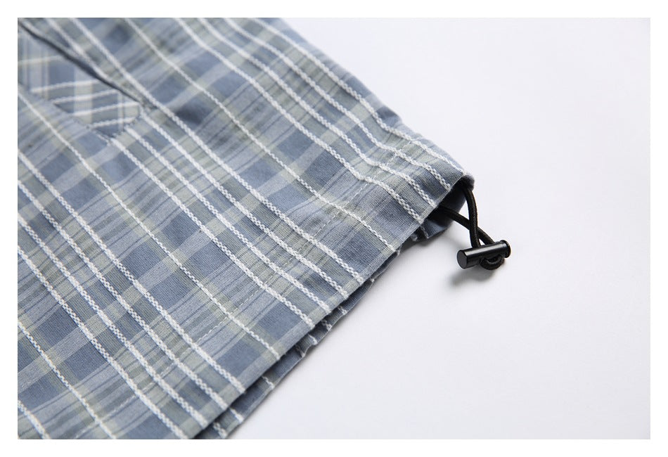 Close-up of blue-gray plaid fabric edge with a black elastic cord and stopper.