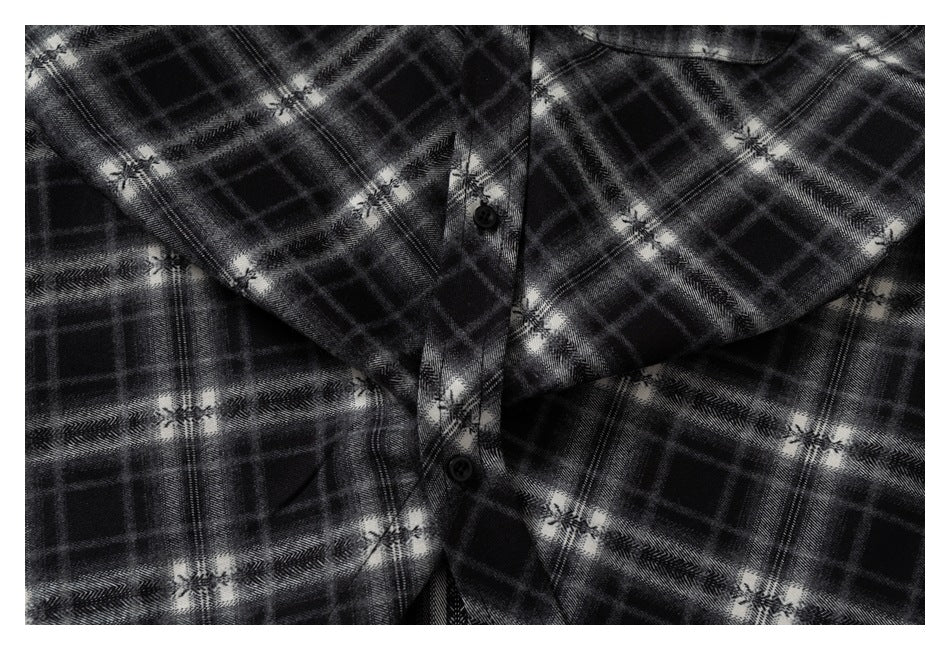 Close-up of the shirt's black buttons and black and gray plaid fabric.