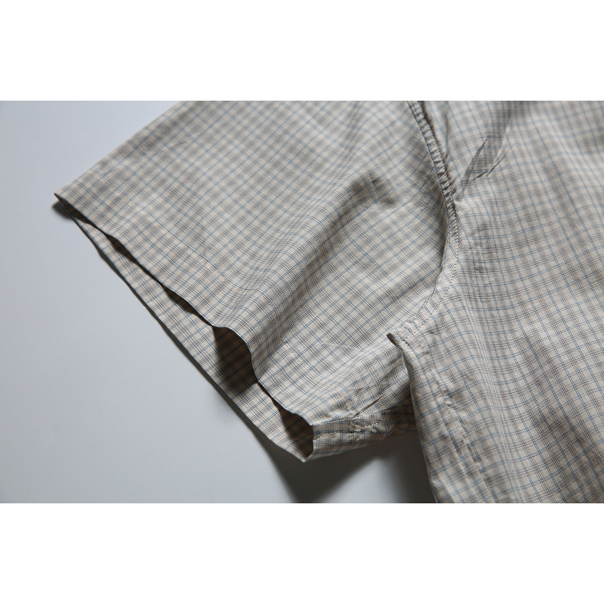 Close-up of the plaid shirt’s short sleeve and stitched sleeve opening.