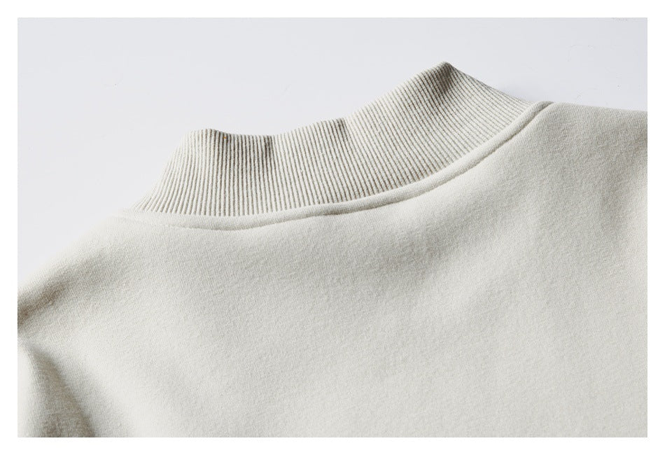 Close-up of an ivory sweatshirt neckline with a tall ribbed collar and smooth body fabric.