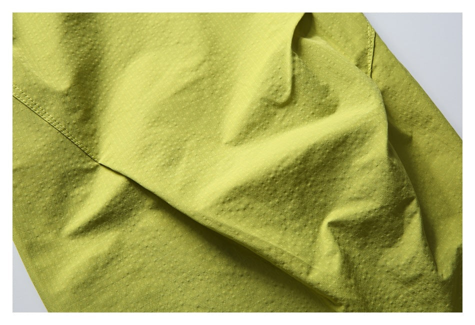 Close-up of lime-yellow shorts fabric showing its subtle grid texture and stitched seam.