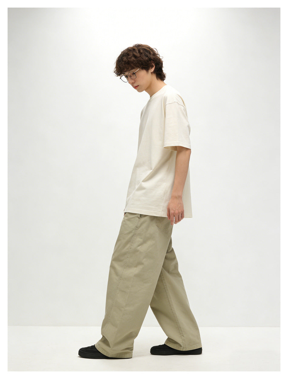 Side view of a model walking in an off-white short-sleeve T-shirt and loose light khaki trousers.