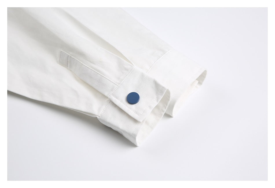 Close-up of a white sleeve cuff with a dark blue button and a narrow cuff strap.
