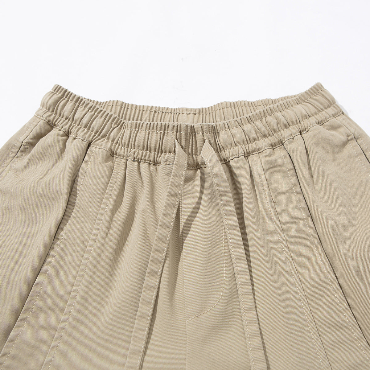 Close-up of beige wide-leg pants showing the gathered elastic waistband, matching drawstring and stitched panels.