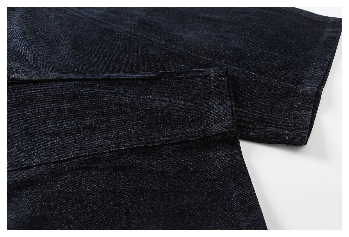 Close-up of black pants showing overlapping fabric panels and a stitched edge.