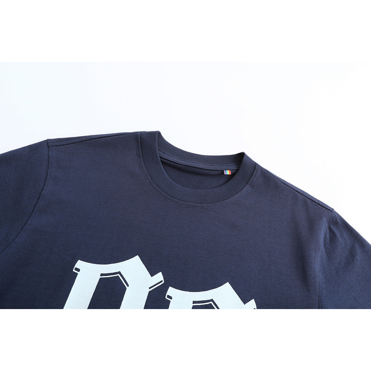 Close-up of a navy crew-neck T-shirt showing the collar, shoulders and partial white Gothic-style chest graphic.
