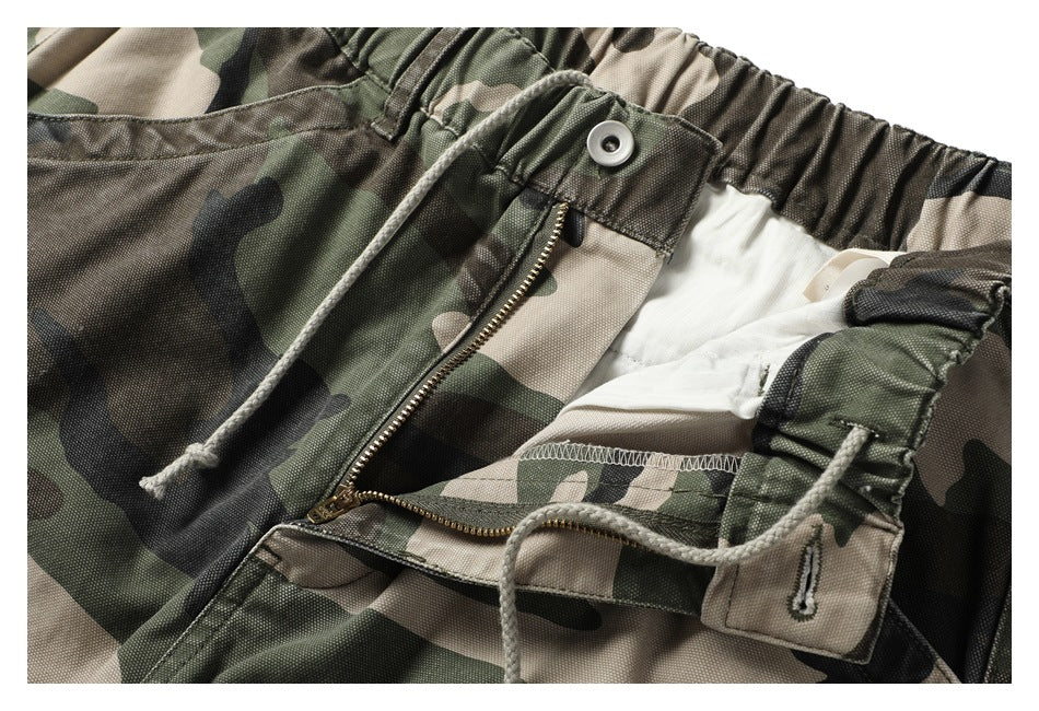 Close-up of the camouflage pants with the waistband open, showing the button, zipper fly and inner lining.