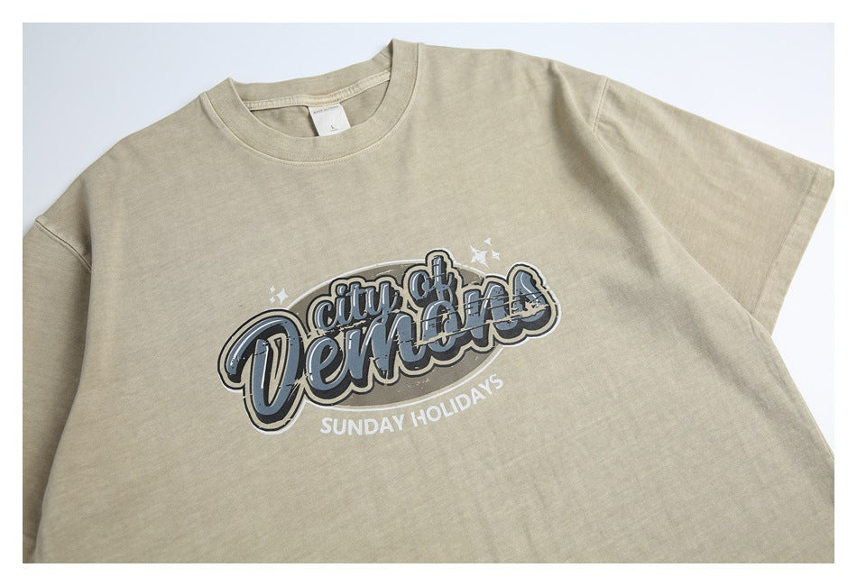 Close view of a beige short-sleeve T-shirt with a large distressed black, gray, and white chest graphic.