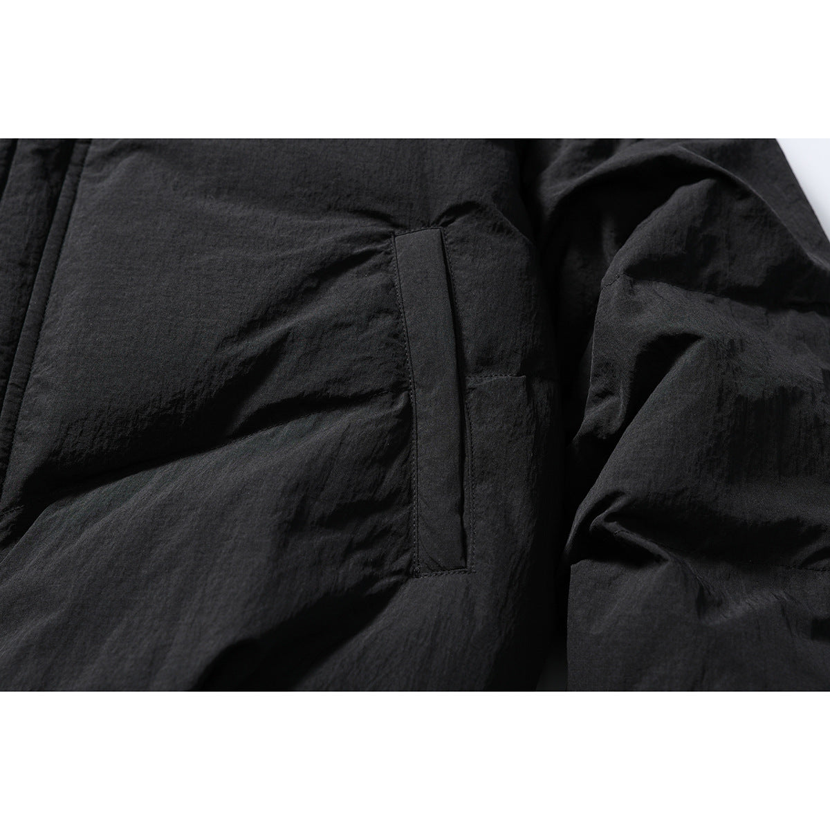 Close-up of the black jacket's vertical side pocket and gathered sleeve.