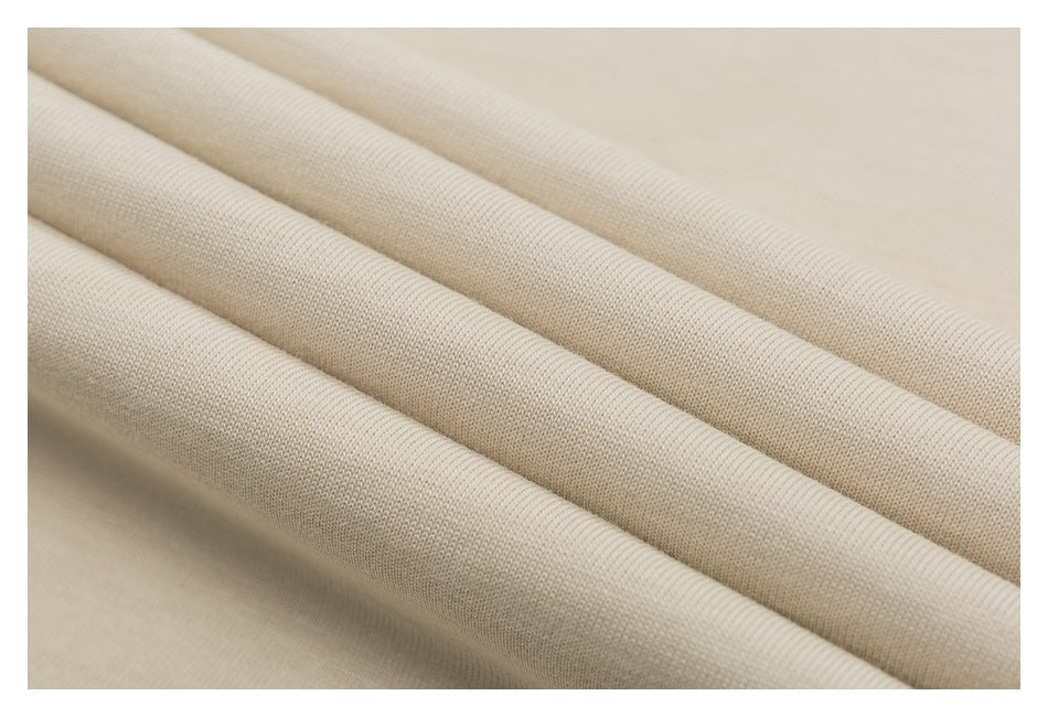 Close-up of folded cream-colored fabric showing its fine knit texture.