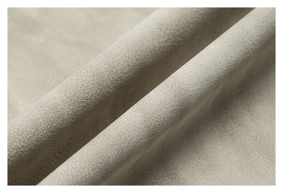 Close-up of light beige fabric folded into soft ridges, showing its fine surface texture.