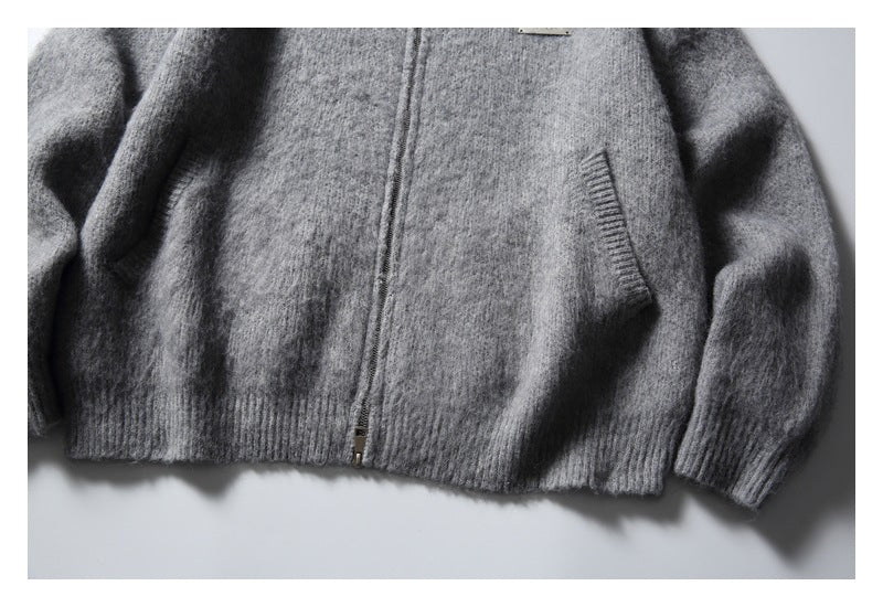 Cropped front view of a gray fuzzy zip-up cardigan laid flat, with slanted pockets and ribbed cuffs and hem.