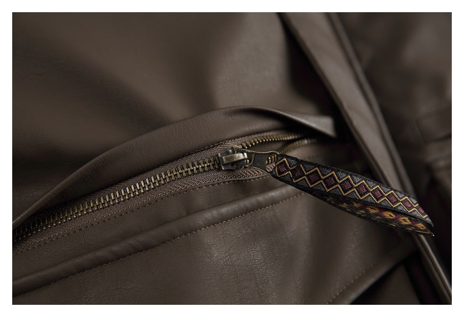 Close-up of a brass-tone zipper with a patterned fabric pull on a dark brown jacket.