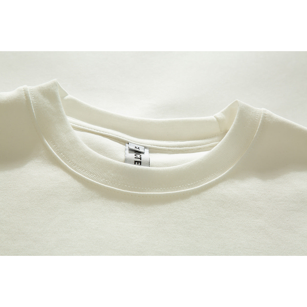 Close-up of an off-white T-shirt's ribbed crew neckline and inner neck label.