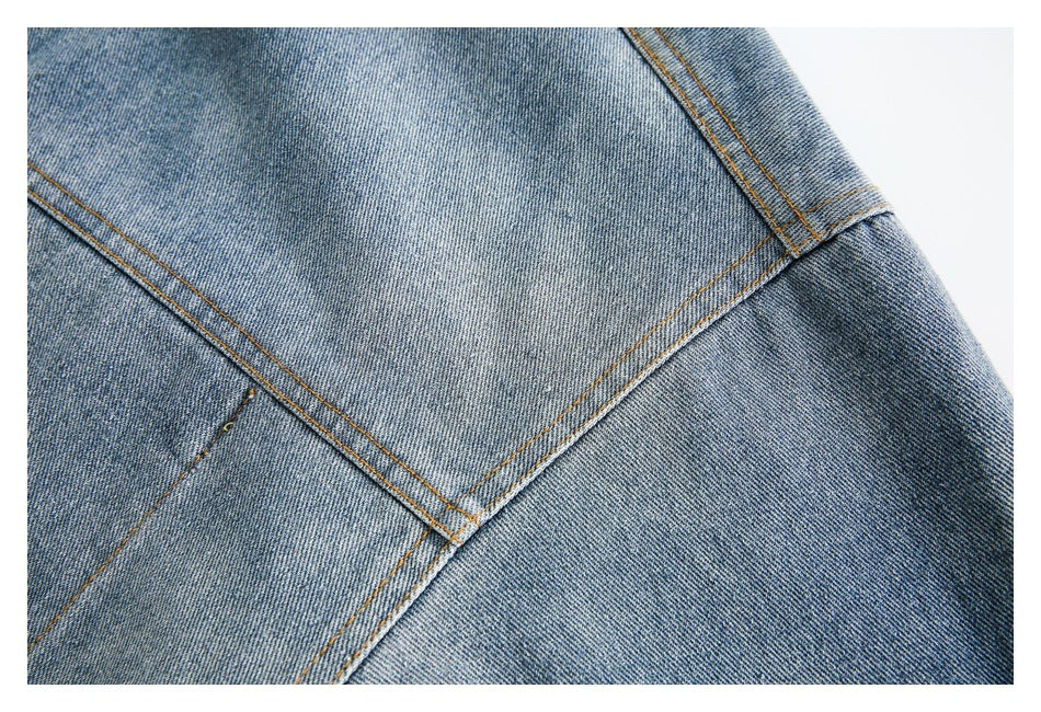 Close-up of faded blue denim panels meeting at a stitched seam with orange topstitching.