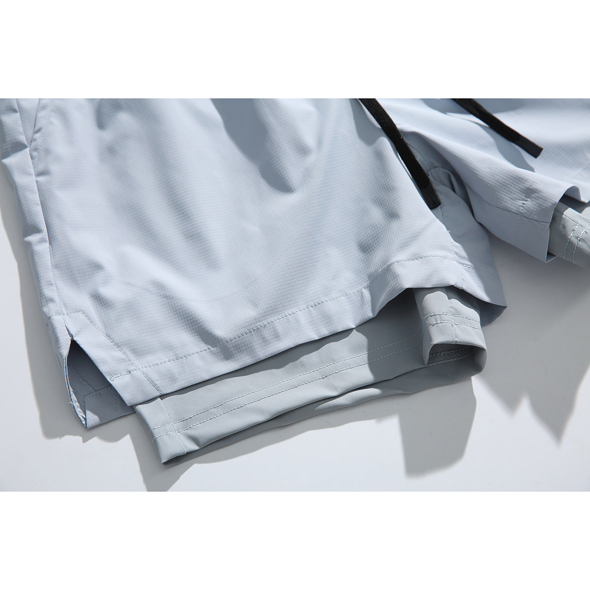Close-up of pale blue-gray shorts showing layered hems and side slits.