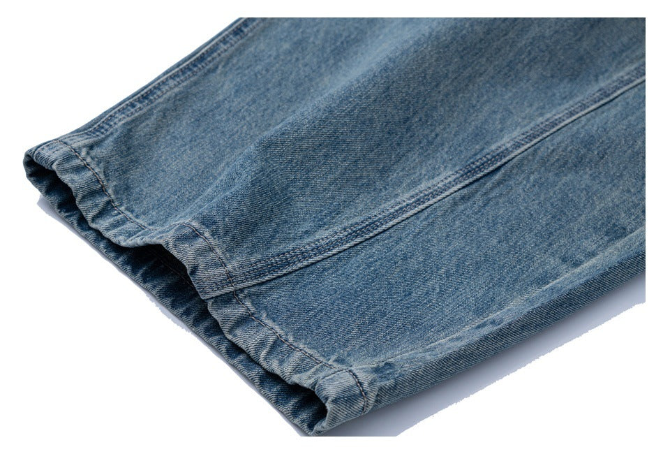 Close-up of the stitched hem on a leg of faded blue jeans.