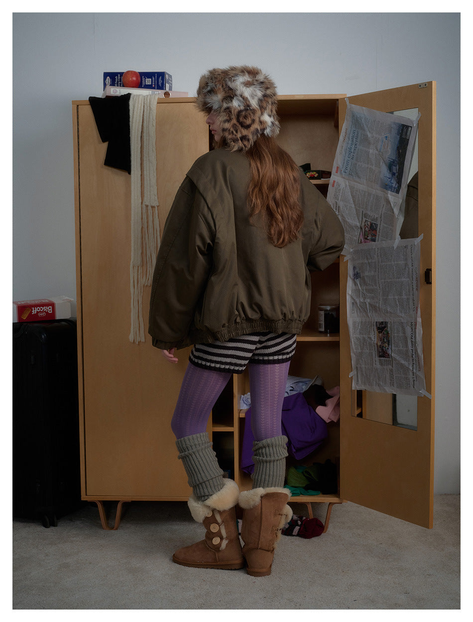 Back view of a person wearing a dark olive bomber jacket with a ribbed elastic hem, styled with winter accessories.