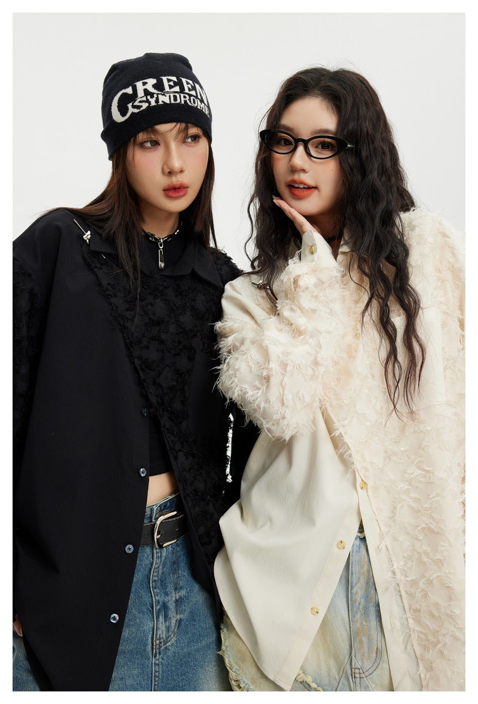 Two models in close-up wearing black and ivory oversized shirts with contrasting textured panels.