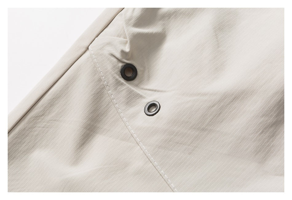 Close-up of two dark metal eyelets set in light beige fabric beside a stitched seam.