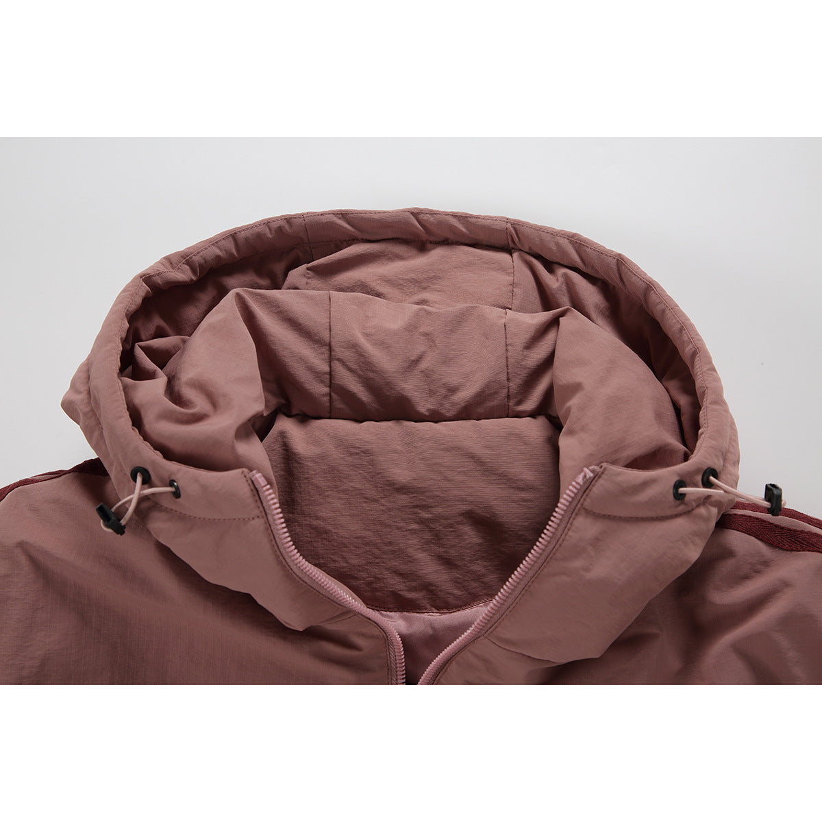 Close-up of a dusty rose jacket hood, drawcord toggles and partially open pink zipper.