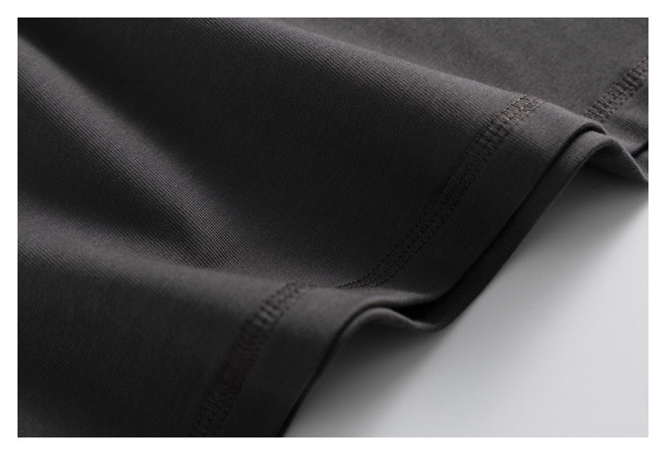 Close-up of charcoal fabric folds and parallel stitching along a folded edge.
