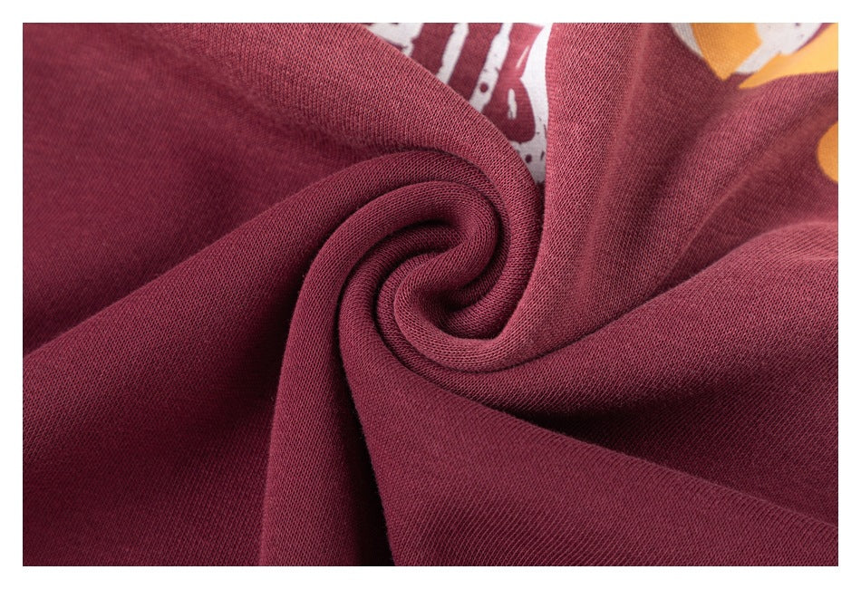 Close-up of burgundy fabric gathered into a spiral, with parts of a printed graphic visible behind it.
