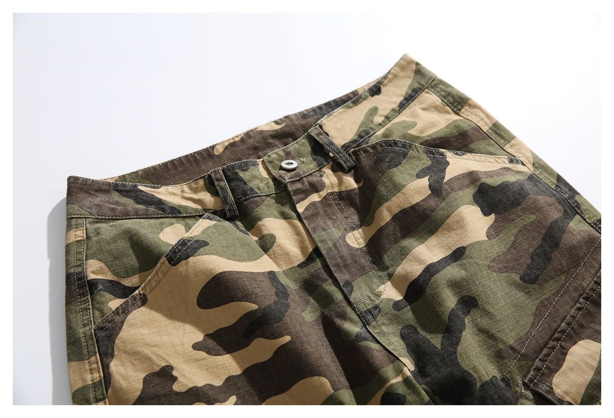 Angled close-up of the front waistband, button and pocket on camouflage cargo pants.
