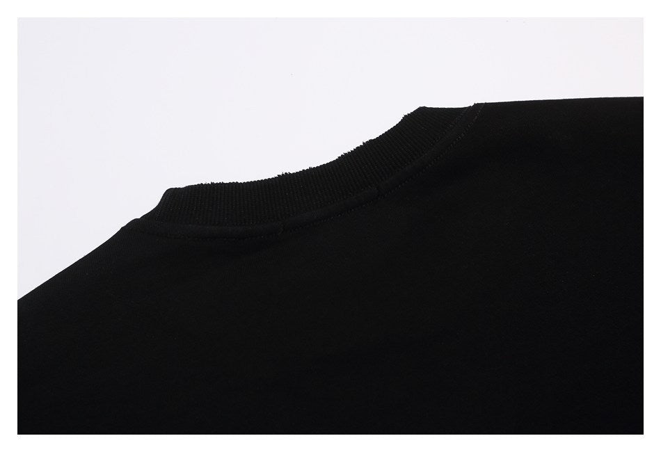 Close-up of the black garment's ribbed crew neckline and shoulder seam.